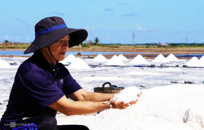 Mr. Phuc examined the white salt grain.  Photo: An Minh