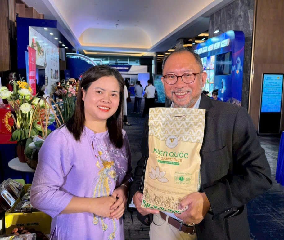 An international delegate buys a bag of Kien Quoc organic rice, cultivated in clam worm farms, to bring home as a gift for his family. Photo: Dinh Muoi.